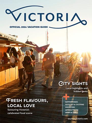 The cover of Victoria's Official 2024 Vacation Guide. A crowd of people are on a pier at Victoria's Inner Harbour at sunset on a summer day.